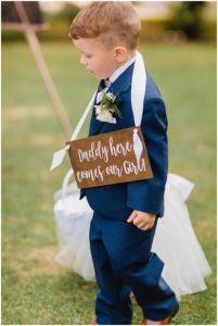 a boy with a sign around his neck for his mom's whimsical wedding