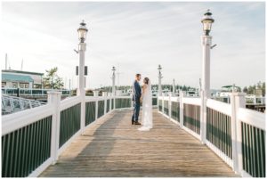a bride and groom walking away on a pier at roche harbor after their wedding during sunset
