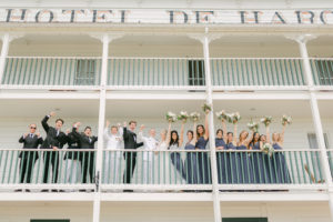 a bridal party cheering and looking at the camera on the porch of Hotel De Haro at Roche Harbor 