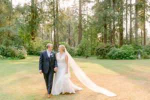a man and woman walking together towards the camera and looking at each other during sunset at their lakewold gardens wedding
