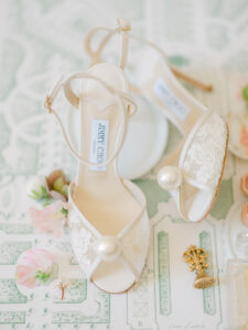 a pair of jimmy choo bridal shoes with lace and a large pearl on the end for a french micro wedding