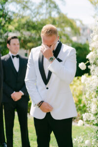 a groom in a white suit crying at his wedding 