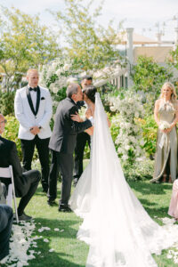 a bride's father gives her away at her wedding and kisses her on the cheek