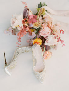 wedding shoes sitting next to a wedding bouquet