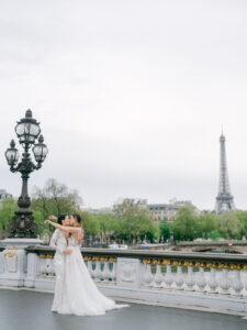 two brides on a bridge in Paris kissing with the eiffel tower behind them