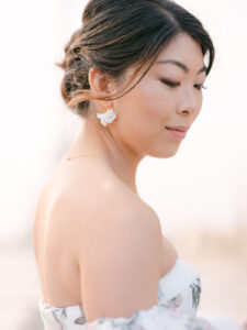 a closeup of a bride looking down showing her earrings off with the iffel tower behind them