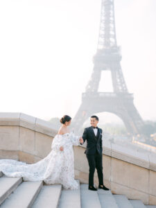 a bride and groom walking down some stairs with the eiffel tower in the background