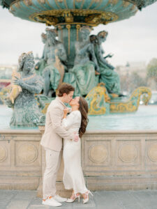 a man and woman kissing in front of a fountain in paris for their engagement session