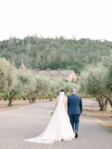 a bride and groom walking away from the camera in napa valley at their winery wedding venue in california