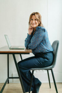 a woman sitting in a chair in front of a laptop smiling at the camera