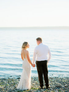 bride and groom holding hands on a beach at their elegant backyard weddings in seattle washington taken by courtney bowlden photography