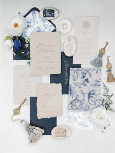 a wedding invitation suit flatlay thats blue, gold and white