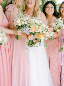a bride and her bridesmaids holding their flowers and looking away from the camera