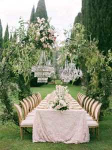 a wedding reception table with pink and gold accents and floral arches holding chandeliers over the table