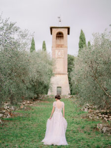 a bride walking away from the camera up a hill towards a tower at villa cetinale