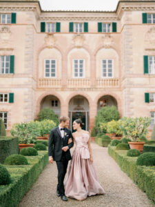 a bridein a pink dress walking with her groom in front of cetinale in tuscany italy for their wedding