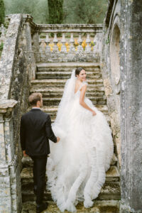 a bride and groom walking up a stojne staircase in the back of villa cetinale in tuscany italy