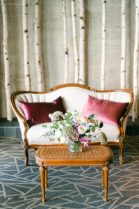 a couch with aspen trees behind it and a floral arrangement on a table in front of it