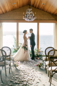 a bride and groom standing in front of large windows overlooking the Seattle sound at their Edgewater Hotel Wedding