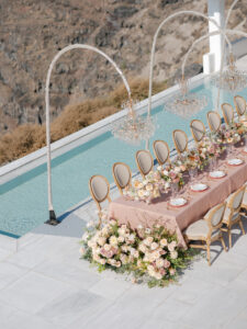 a pink wedding reception table near a pool in santoini greece