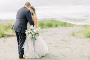 a bride and groom embracing on the beach at seabrook in washington for their coastal wedding