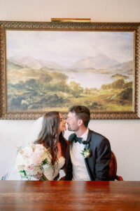 a couple about to kiss while sitting down in front of a beautiful old portrait at their lairmont manor wedding