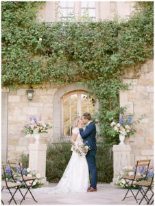 a bride and groom kissing between floral pillars at their wedding at sunstone winery