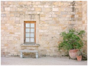 a tan brick wall and a bench with a plant next to it at sunstone winery