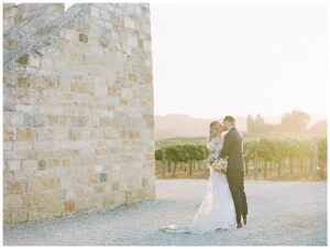 a bride and groom kissing during sunset at their sunstone winery wedding