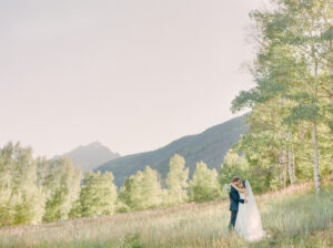 a bride and groom facing each other with mountains in the background