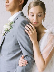 a bride hugging her groom from behind and looking down on the ground