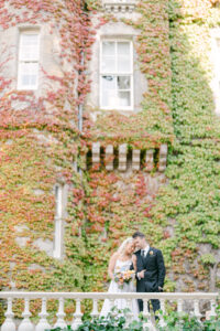 a bride and groom with their foreheads together in front of a very colorful ivy wall at carlowrie castle in scotland taken by their wedding destination photographer