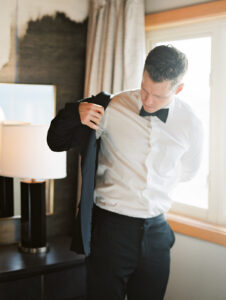 a groom getting his suit on in his hotel room