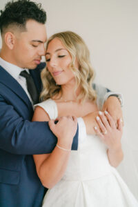 a groom holding his bride and looking at her while she looks away