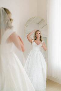 a bride looking in the mirror fixing her veil
