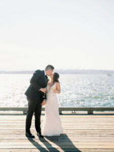 a bride and groom kissing on the pier at their woodmark hotel wedding during sunset