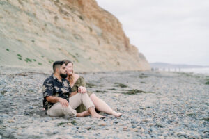 a couple sitting on the beach at torrey pines