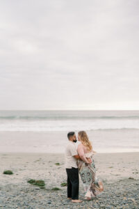 a man and woman embracing on the beach for their Torre Pines engagement