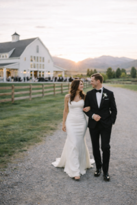 a bride and groom holding hands and walking away while smiling at each other at their river bottoms ranch wedding
