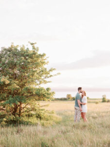 a couple in a field at discovery park in seattle getting their engagement photos taken 