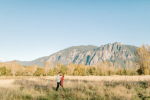 a couple standing in front of a huge mountain in snoqualmie washington getting their engagement photos taken