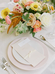 a wedding table design with bright colorful florals and light pink accents