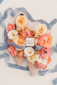 pink shoes filled with flowers and blue ribbon with wedding bands in the center