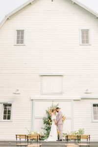 a bride and groom standing in front of a floral arch at their wedding in snohomish