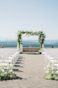 a wedding ceremony site with white chairs and white and green florals overlooking the seattle skyline at a wedding at newcastle golf club