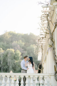 a couple standing on a balcony at Montalvo Arts Center in Saratoga about to kiss