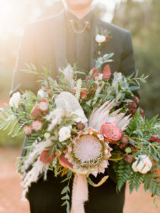 a woman in a black suit holding a large floral arrangement for an elopement in sedona