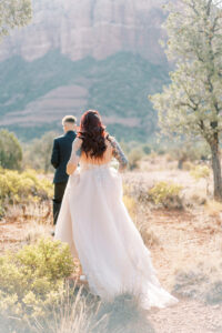 a bride in a pink wedding gown walking with her back to the camera at her elopement in sedona during sunrise