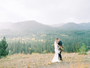 a bride and groom kissing while it rains with mountains in the background at this micro wedding venues in utah