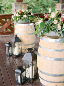 two wooden wine barrels with floral arrangements on them and lanterns for a romantic outdoor wedding at swiftwater cellars in cle elum